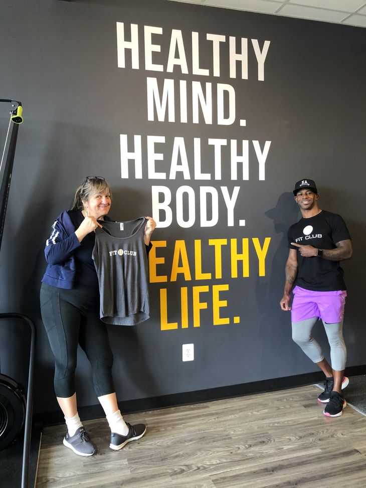 a woman is holding a shirt in front of a wall that says healthy mind healthy body healthy life