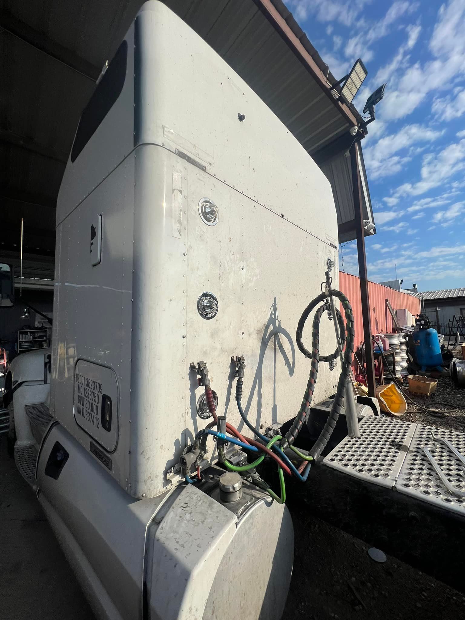 A man is writing on a clipboard in front of a semi truck.