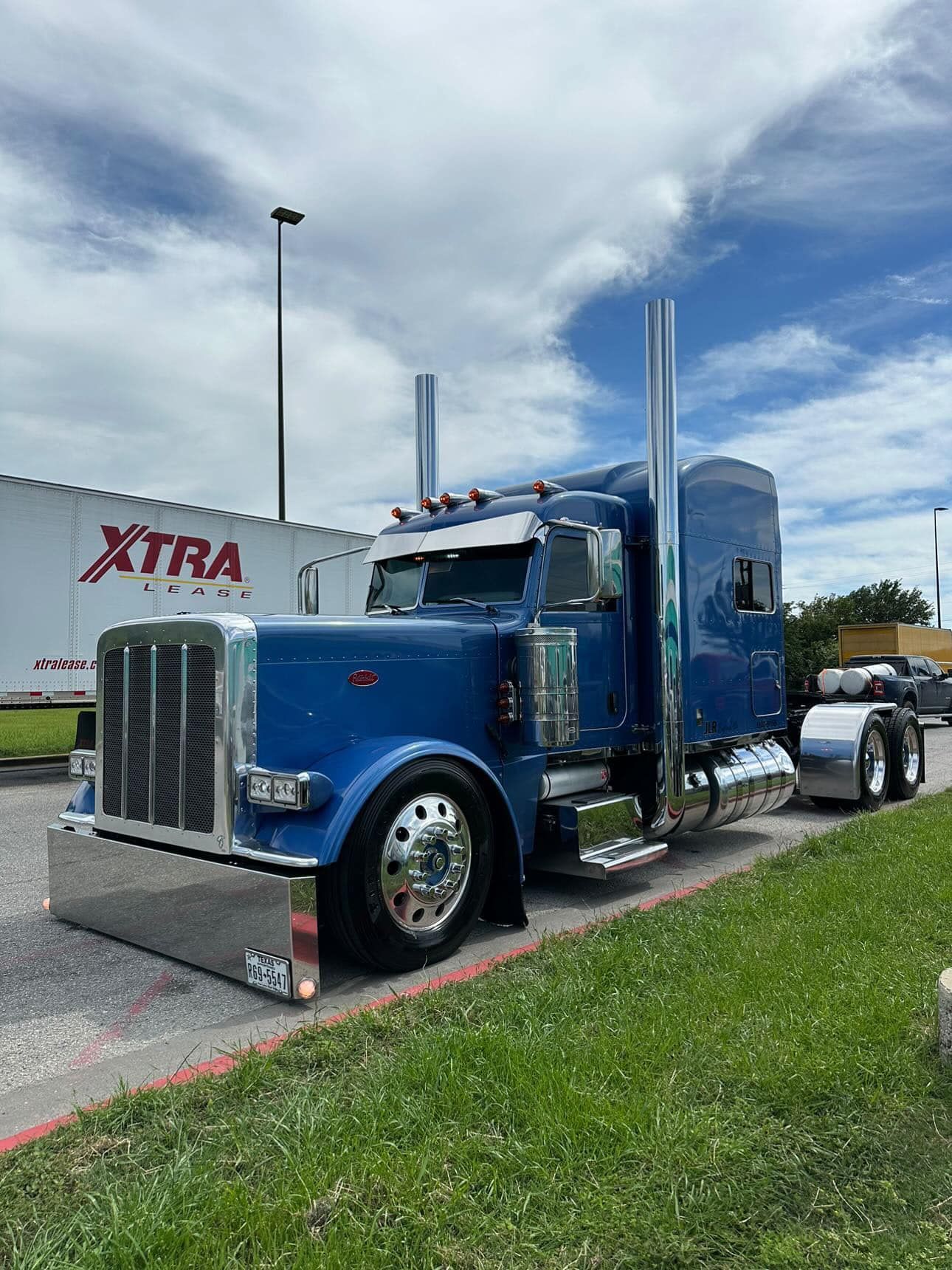 A blue semi truck is parked next to a white trailer.
