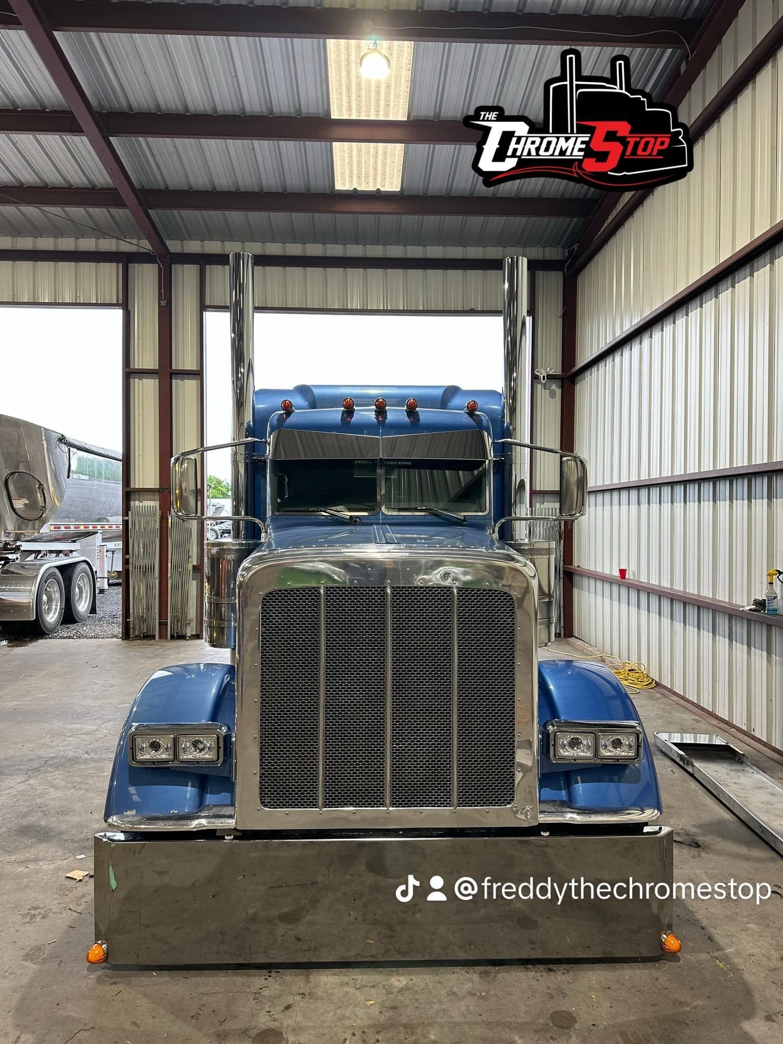 A blue semi truck is parked in a garage.