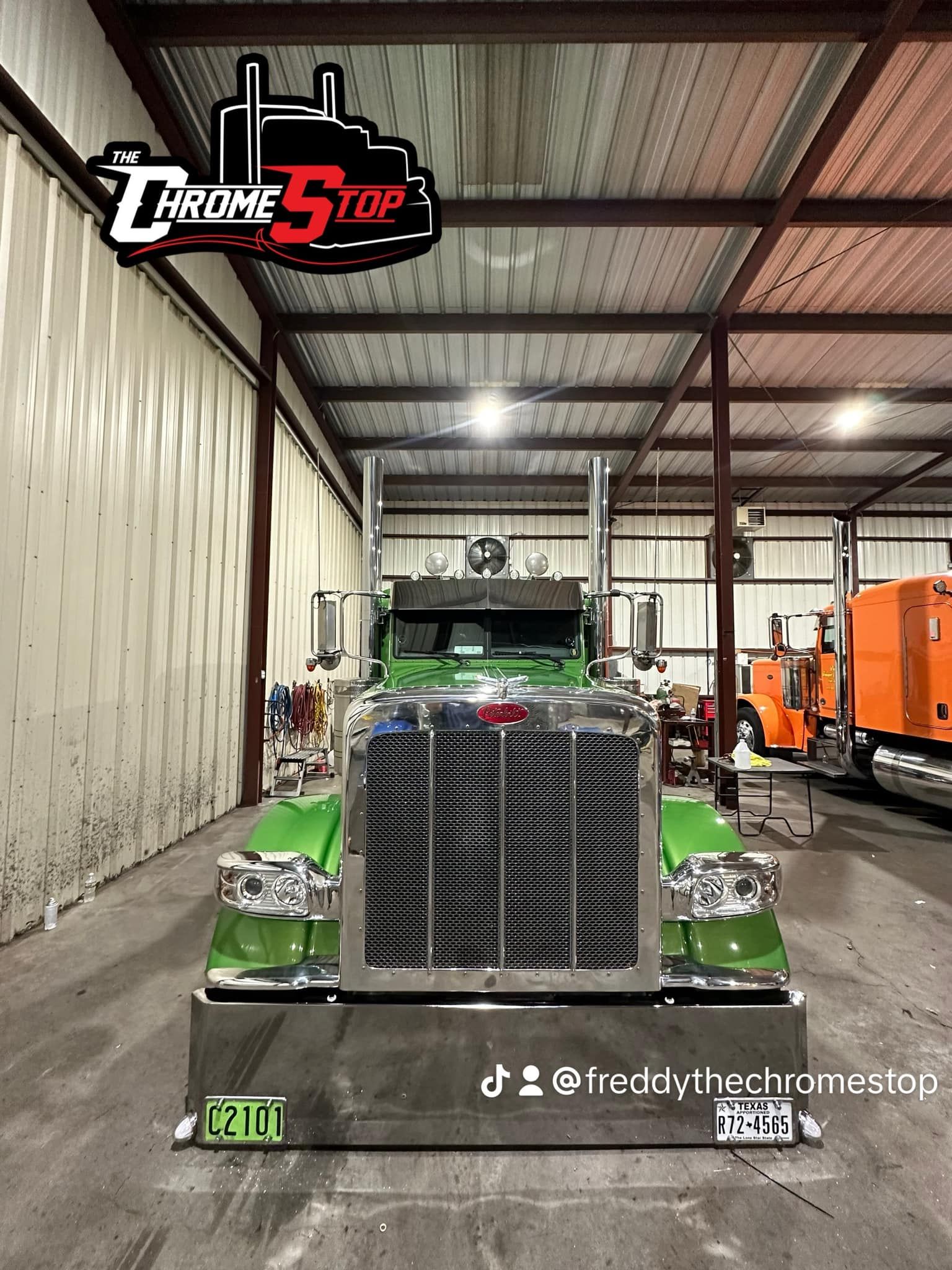 A green semi truck is parked in a warehouse.