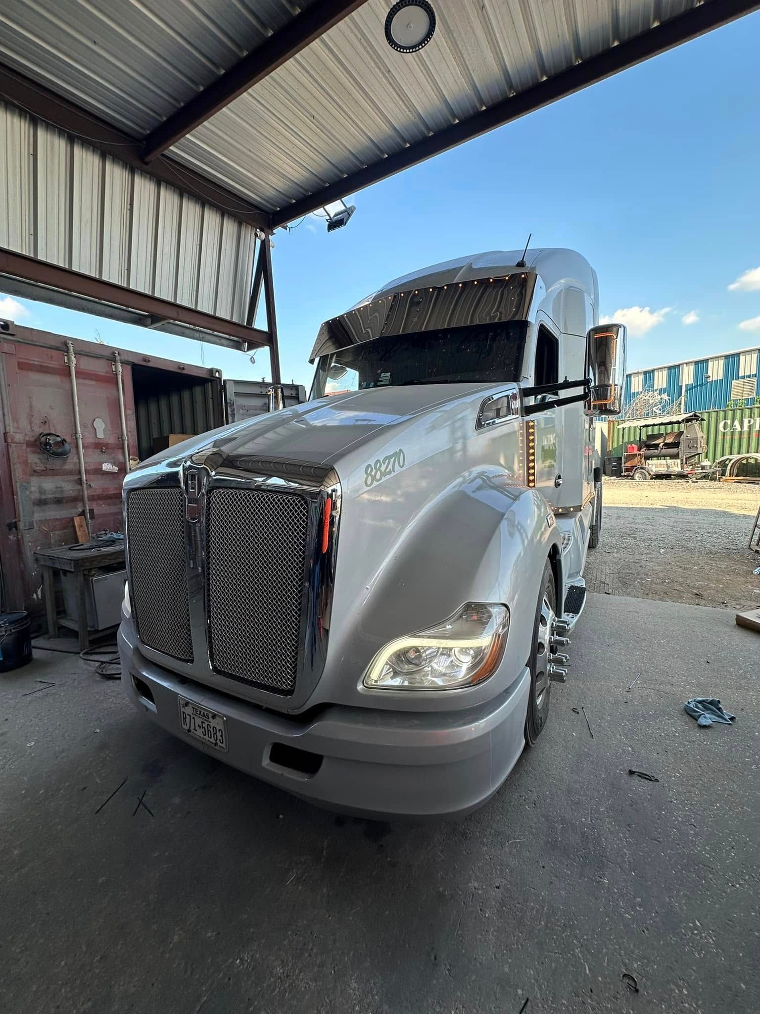A semi truck is parked under a roof in a garage.