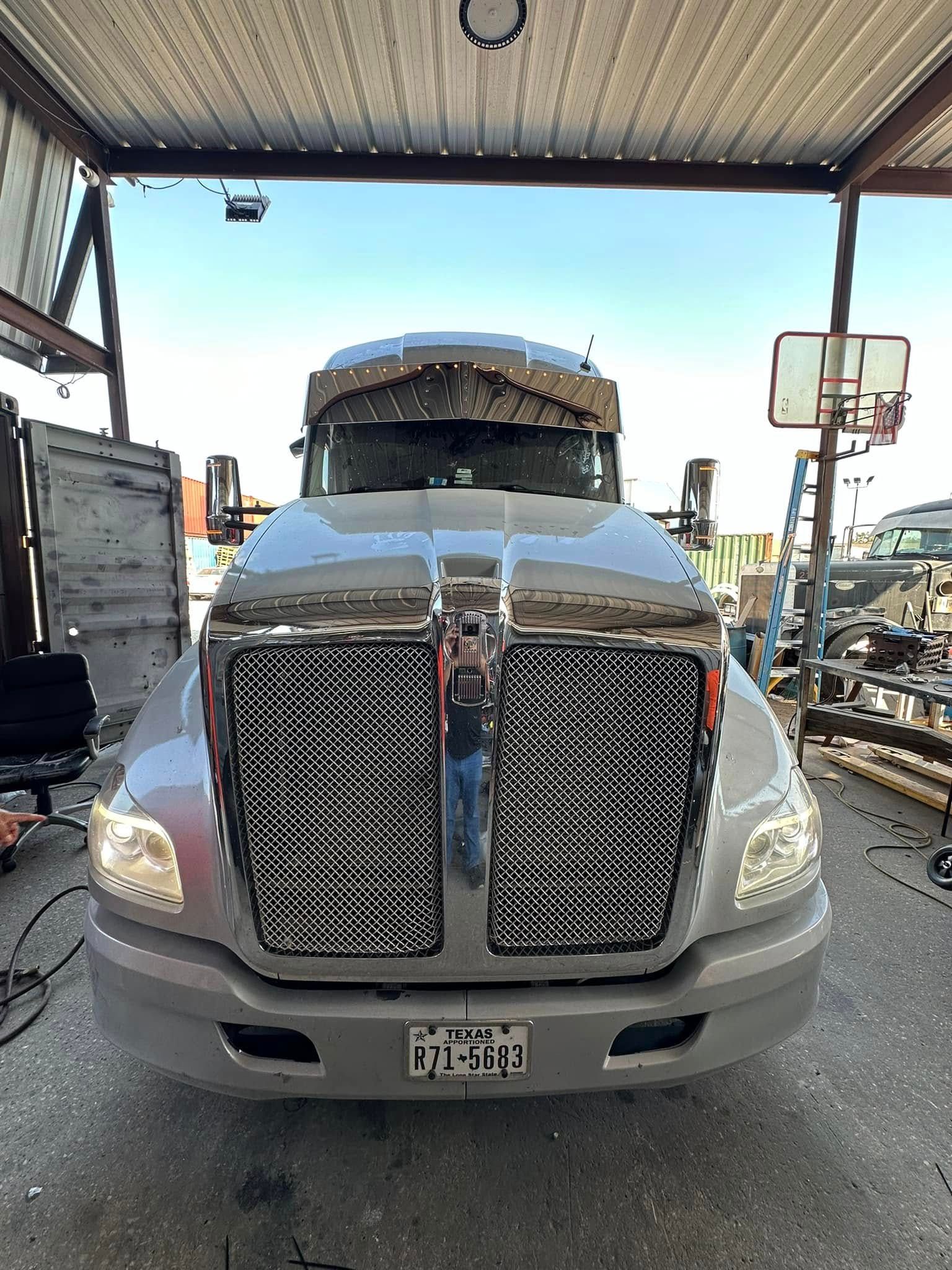 A truck is parked in a garage with a basketball hoop in the background.