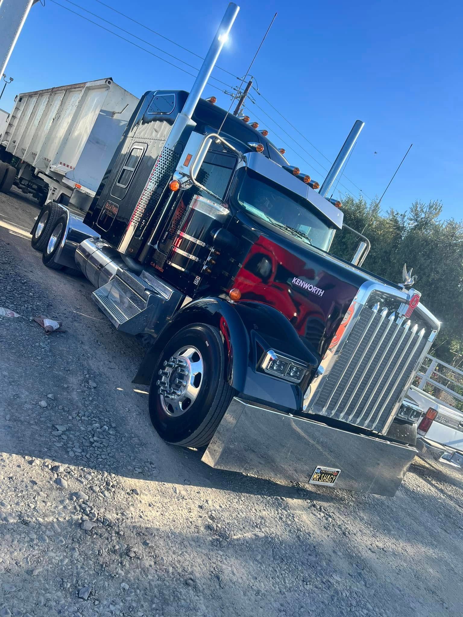 A large semi truck is parked in a gravel lot.