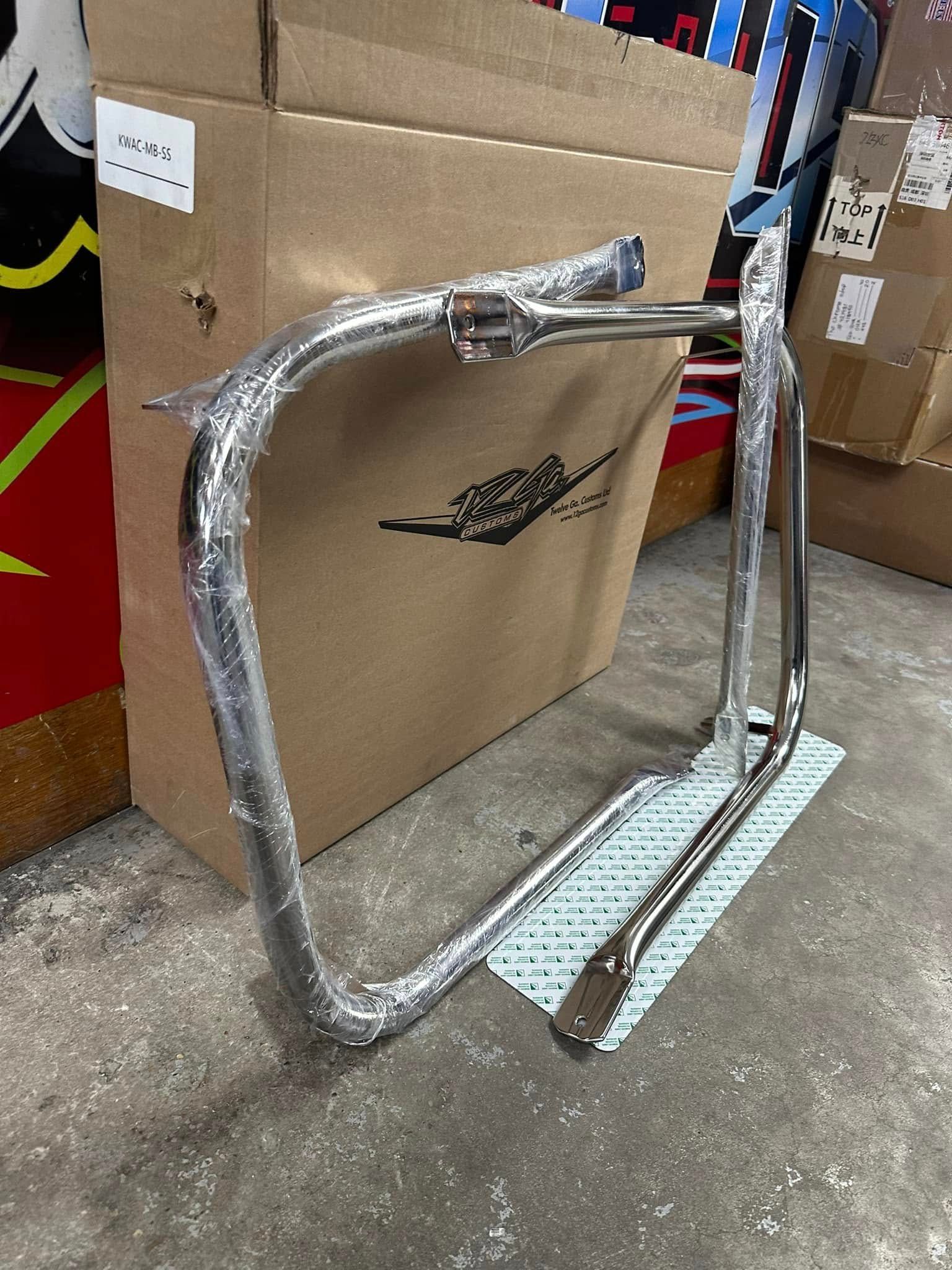 A motorcycle frame is wrapped in plastic and sitting next to a cardboard box.