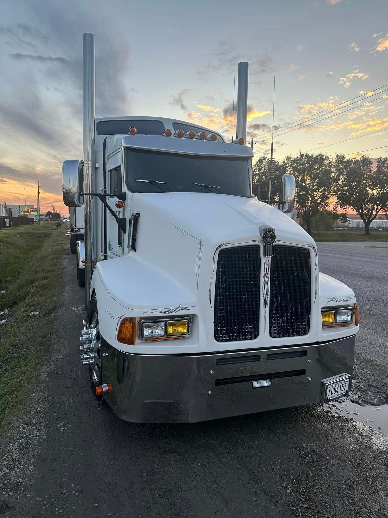A white semi truck is parked on the side of the road.