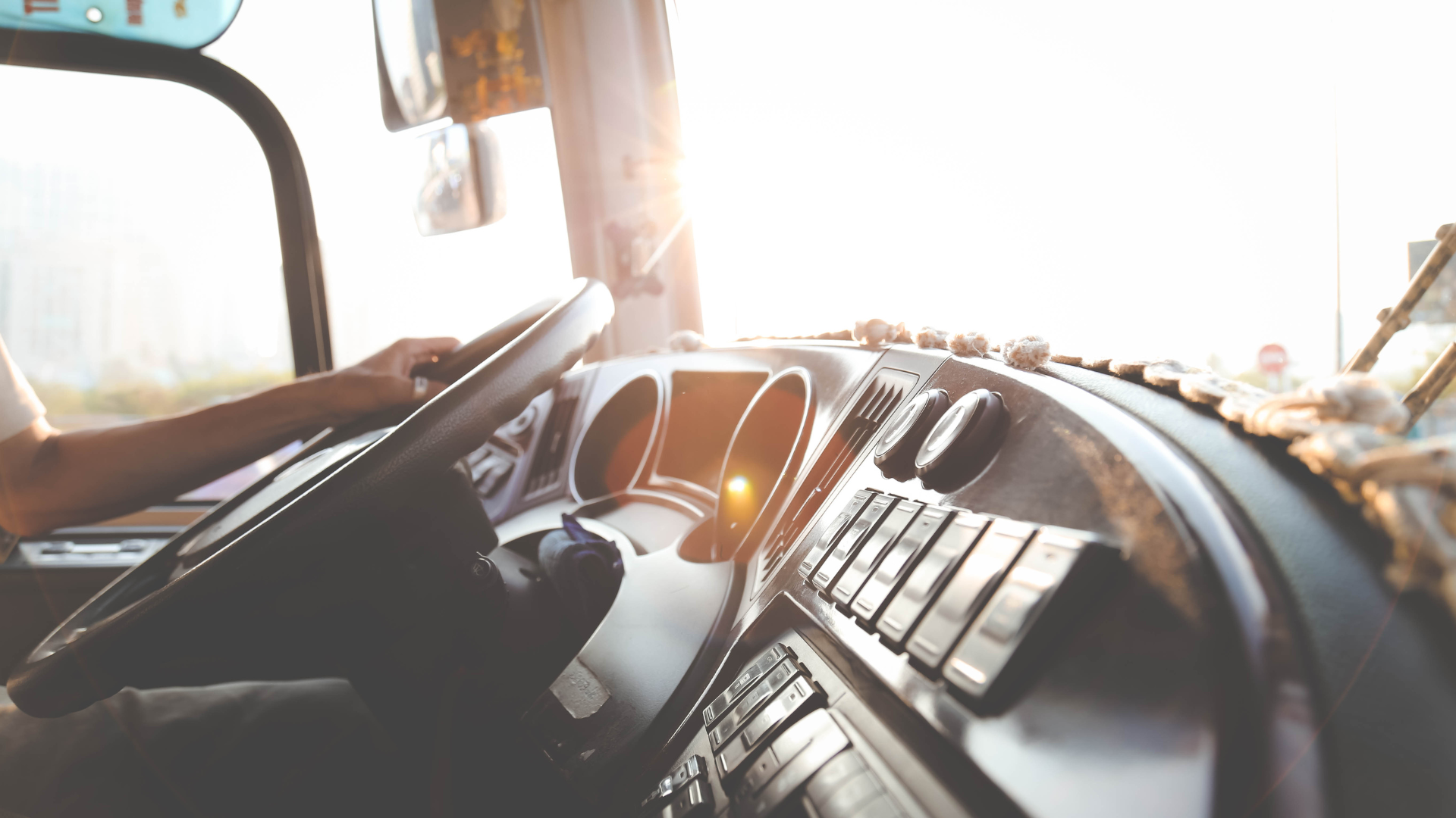 A man is driving a bus with his hands on the steering wheel.