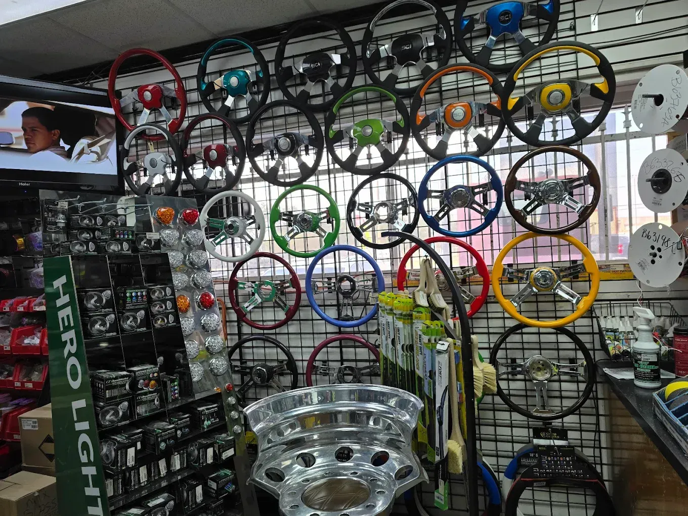 A bunch of steering wheels are hanging on a wall in a store
