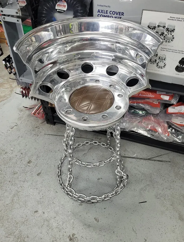 A stool made out of aluminum wheels and chains.