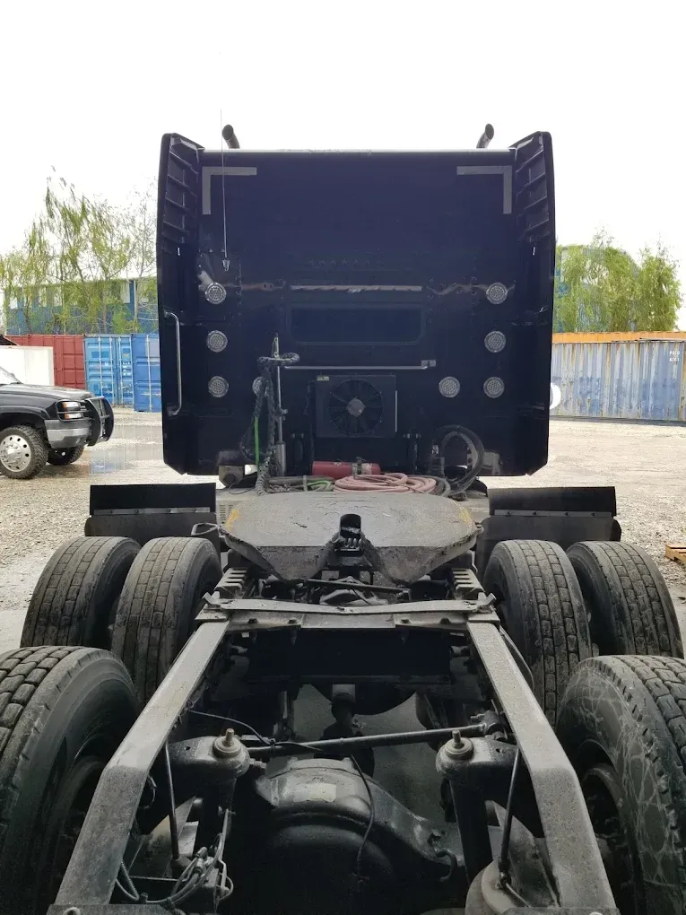 A black semi truck is parked in a parking lot.