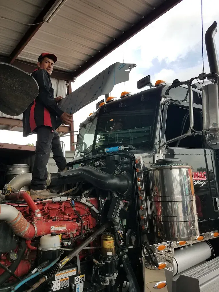 A man is standing on top of a semi truck.