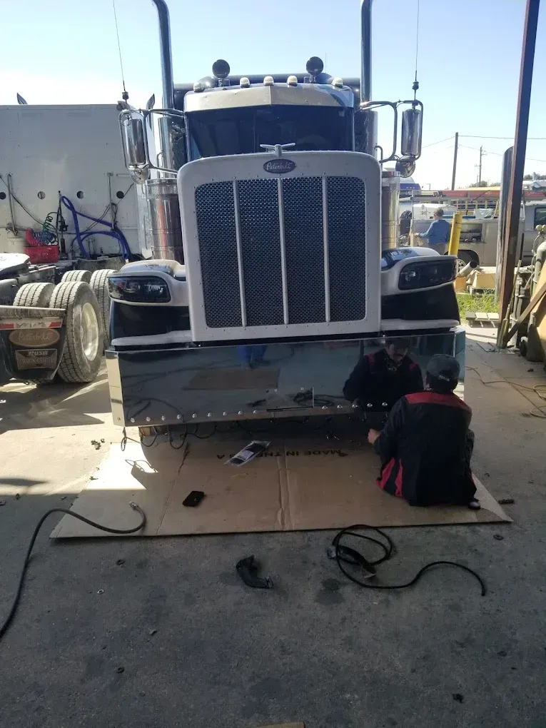 A man is working on the front of a semi truck