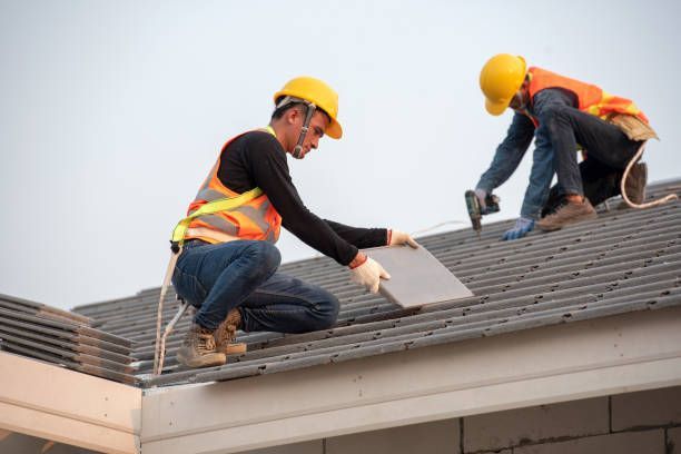 Roof replacement in progress with worker safely working on roof frame.