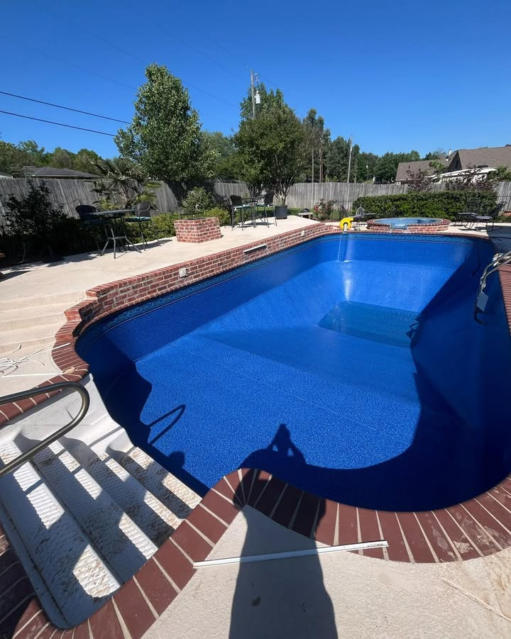 A large blue swimming pool with a brick border