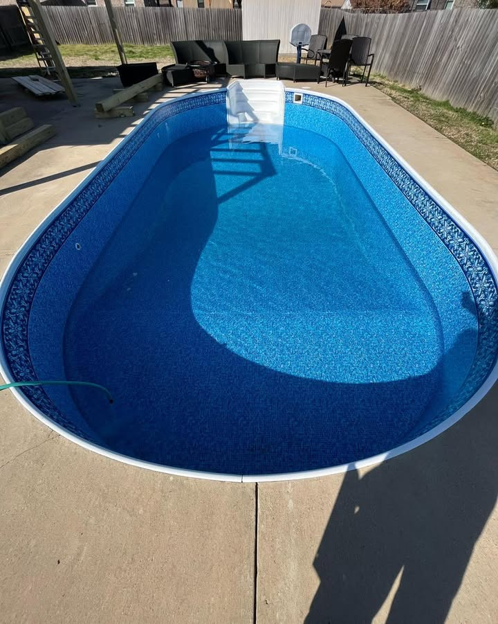 A large blue swimming pool is sitting on top of a concrete deck.