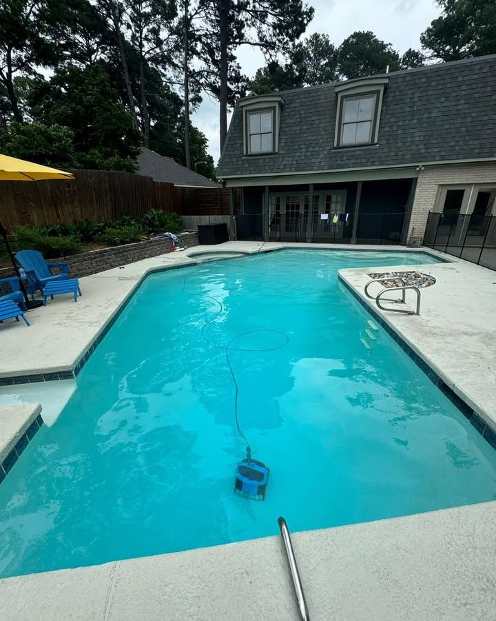 A large swimming pool with a house in the background