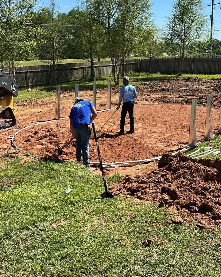 Two men are working on a dirt field with a metal detector.