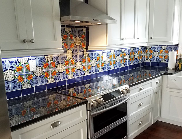 A kitchen with Talavera tile backsplash and black quartz countertops
