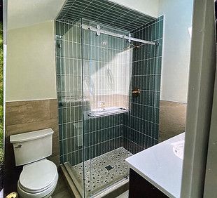 A bathroom vanity with a grey cabinet and stone countertop, next to white wainscoting and a door leading to a room. A bathroom vanity with a grey cabinet and stone countertop, next to white wainscoting and a door leading to a room.