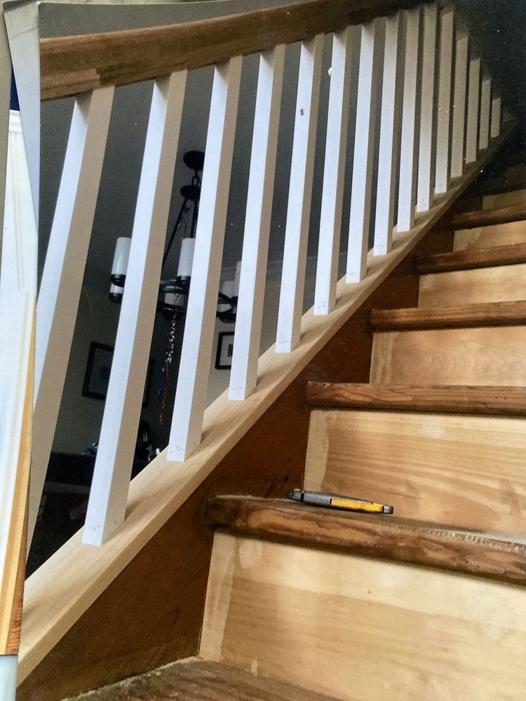 A staircase with wooden treads and white balusters under a wooden handrail, with a utility knife resting on a step.