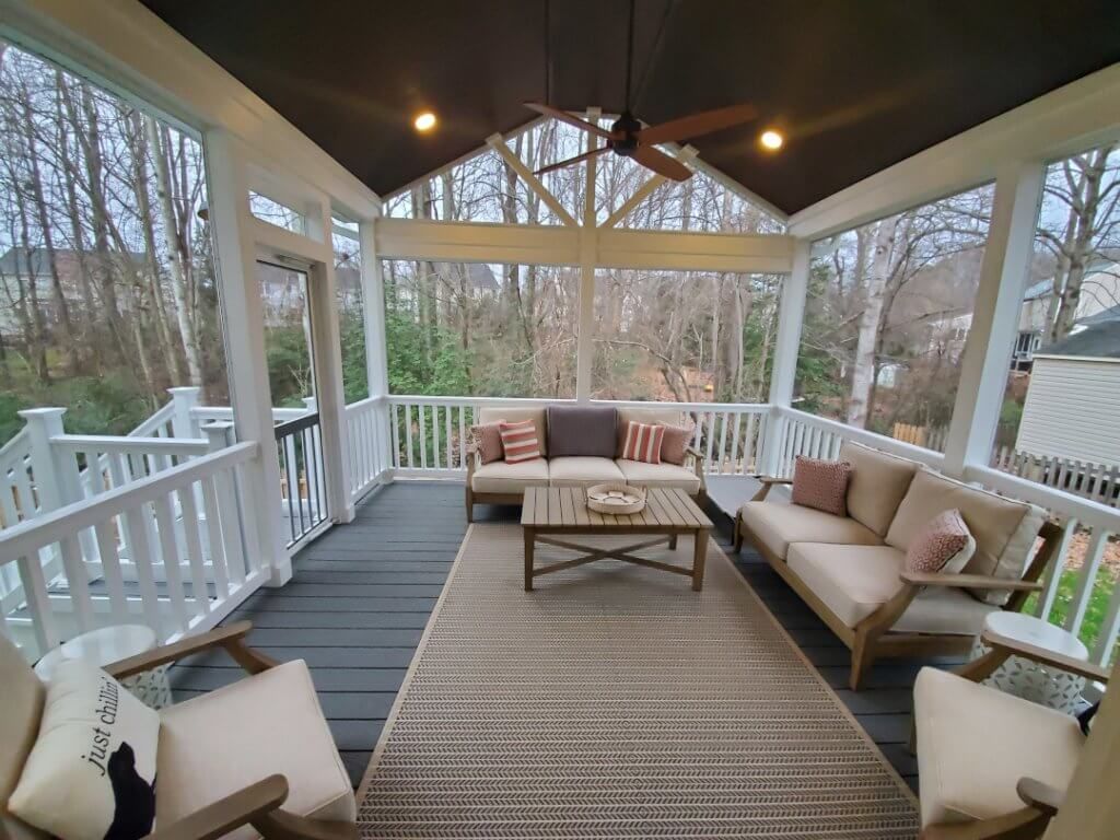 A screened-in porch with furniture and a ceiling fan.