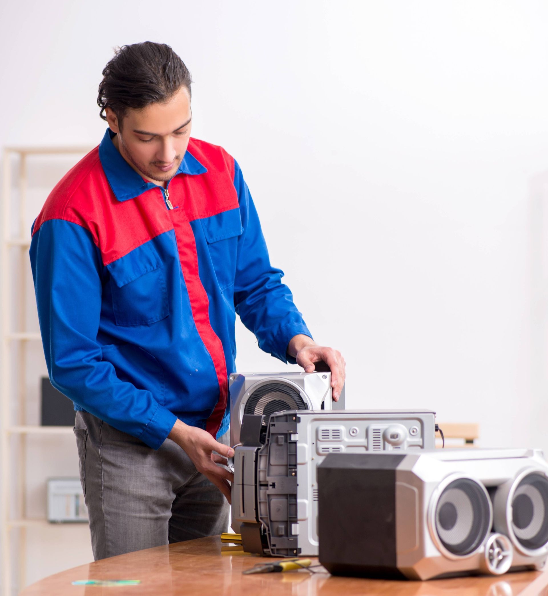 a man in a blue and red jacket is working on a stereo system