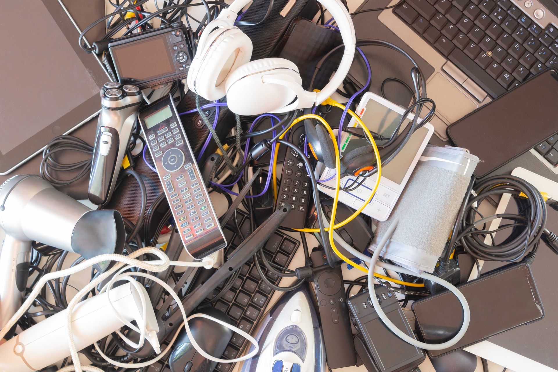 a pile of electronics including a hair dryer and headphones