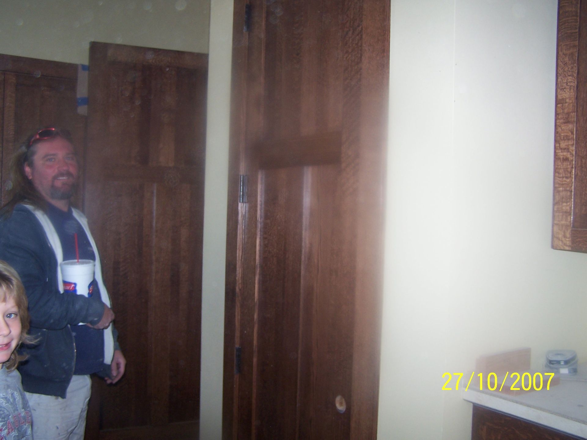 A man and a child are standing in a hallway holding buckets of paint.