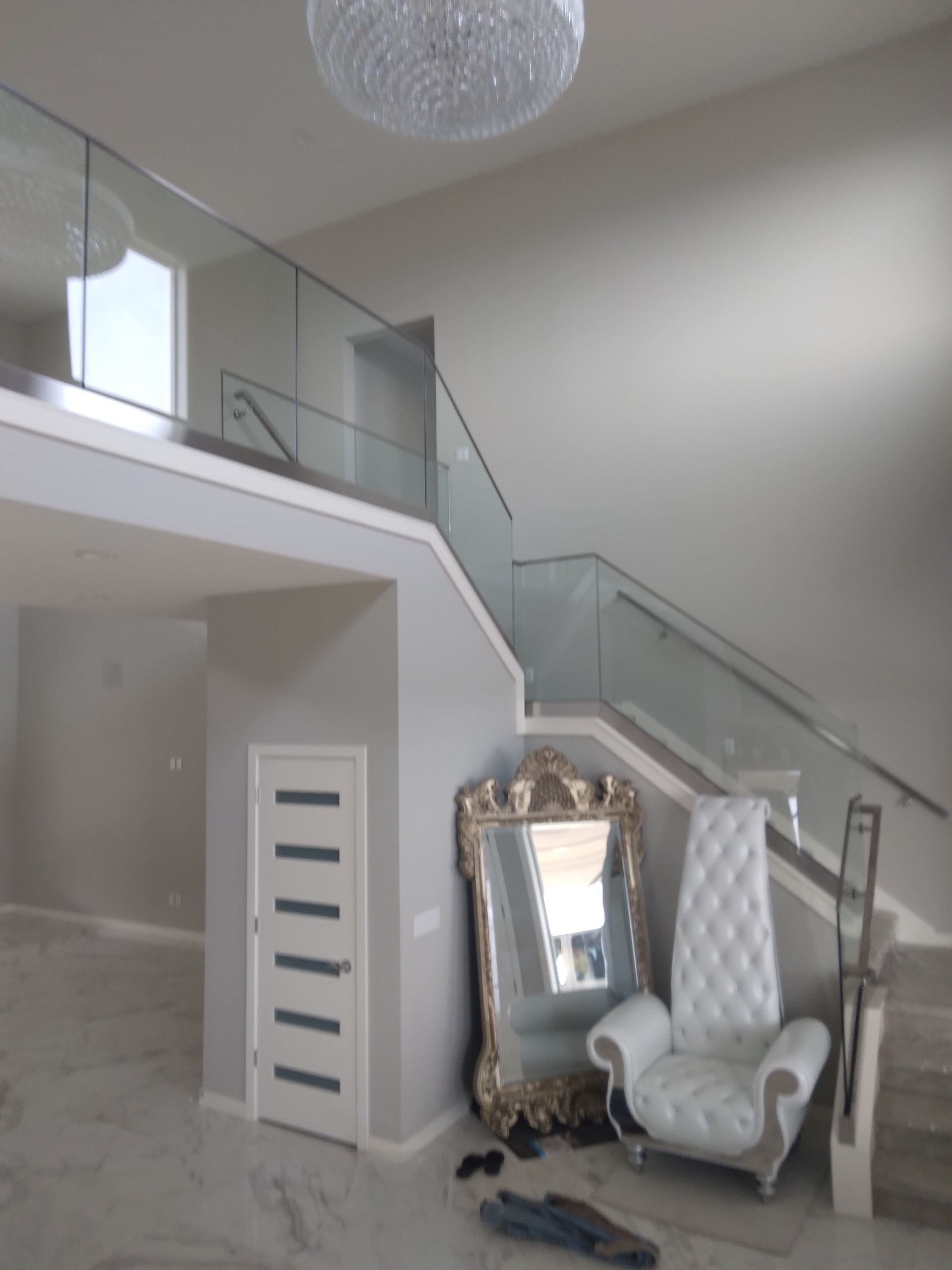 A room with stairs and a chair and a mirror