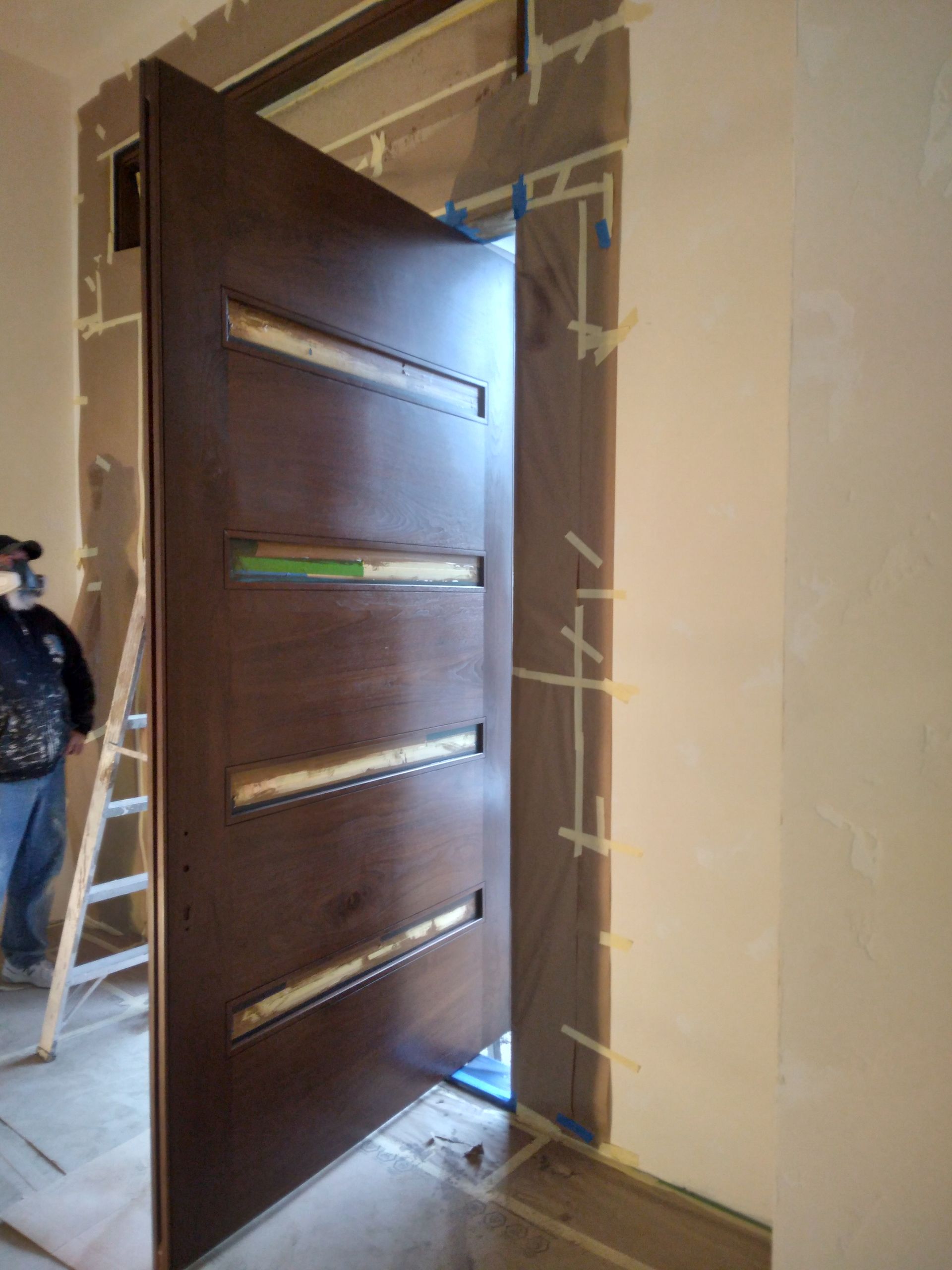 A man is standing next to a wooden door in a room.