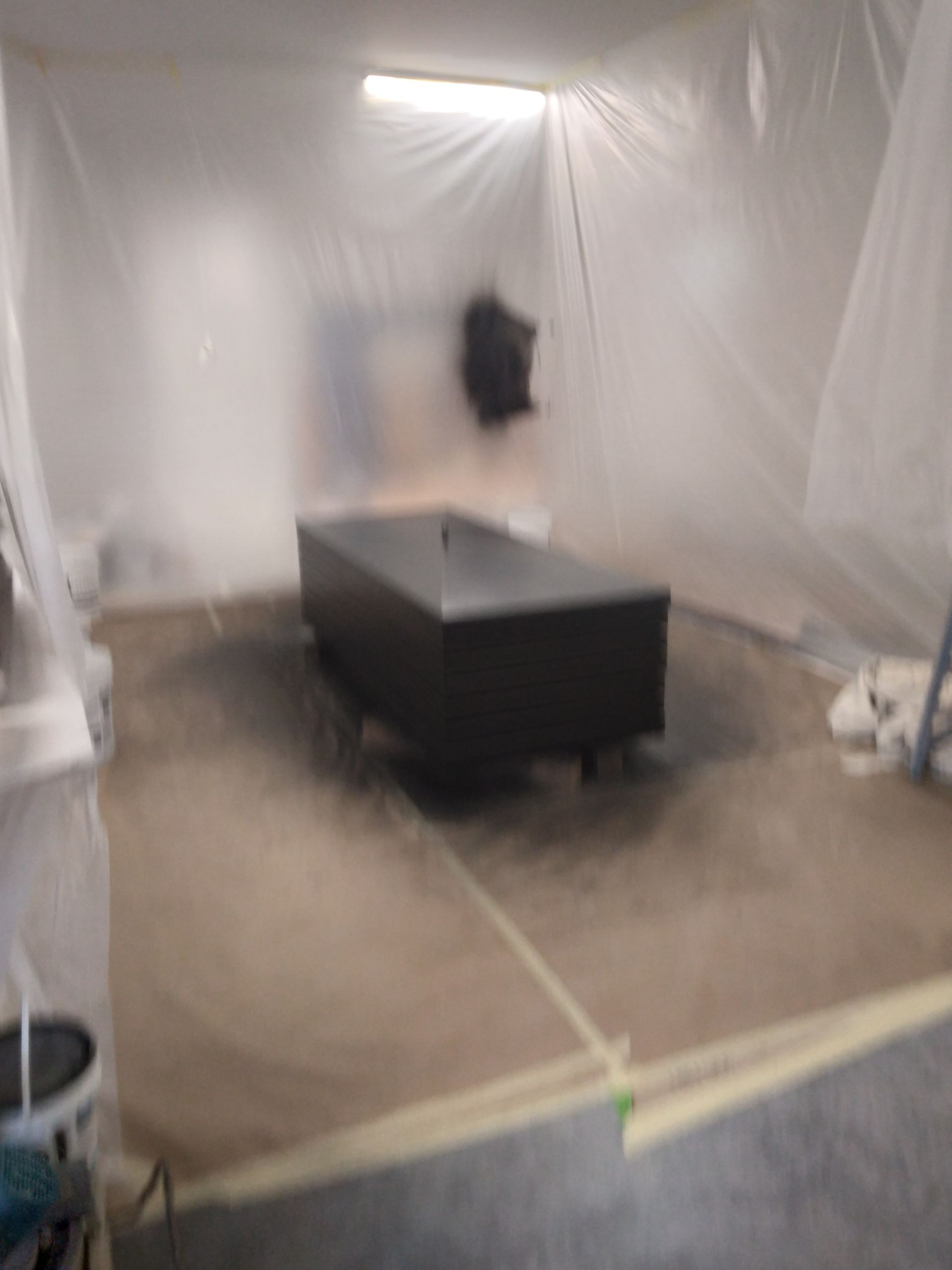 A room with a table and a white tarp on the floor.