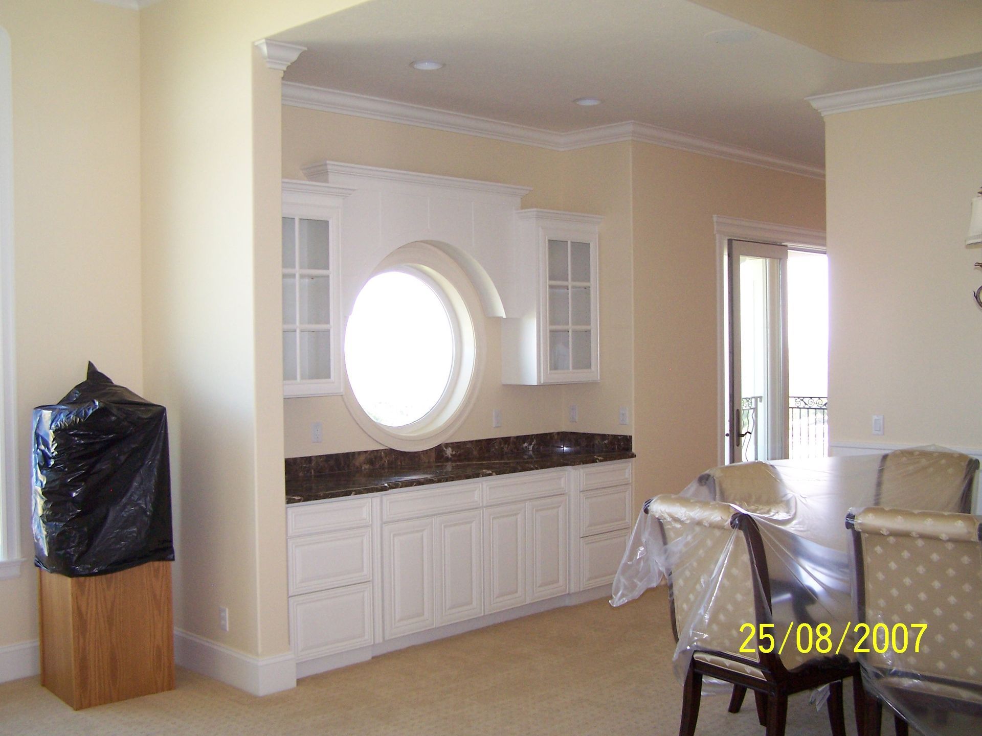 A kitchen with white cabinets and a round window