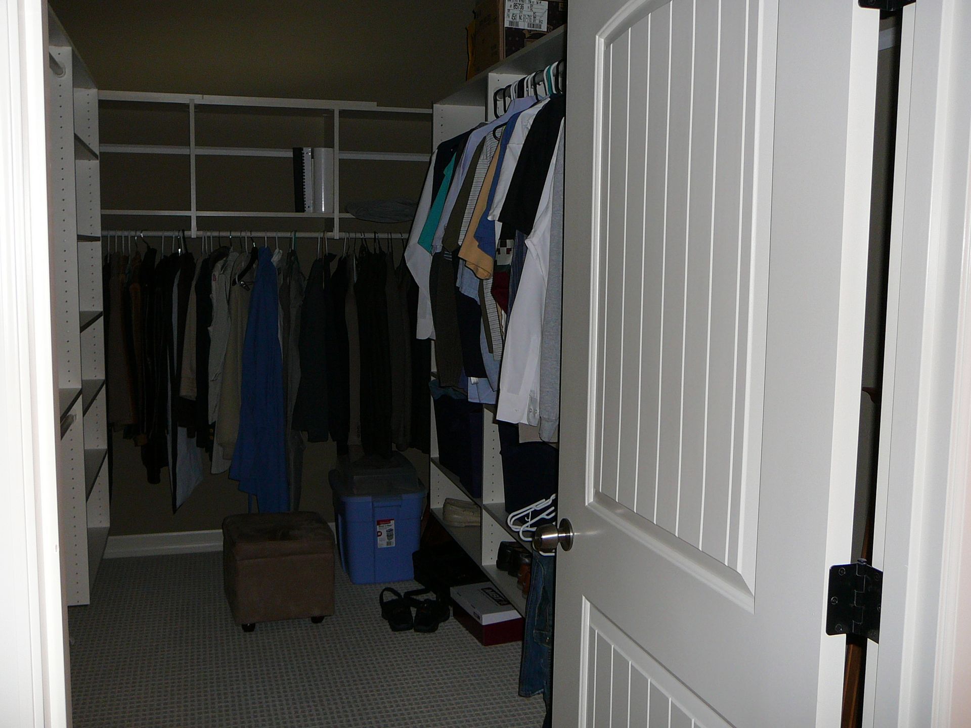 A walk in closet with clothes hanging on racks and shelves