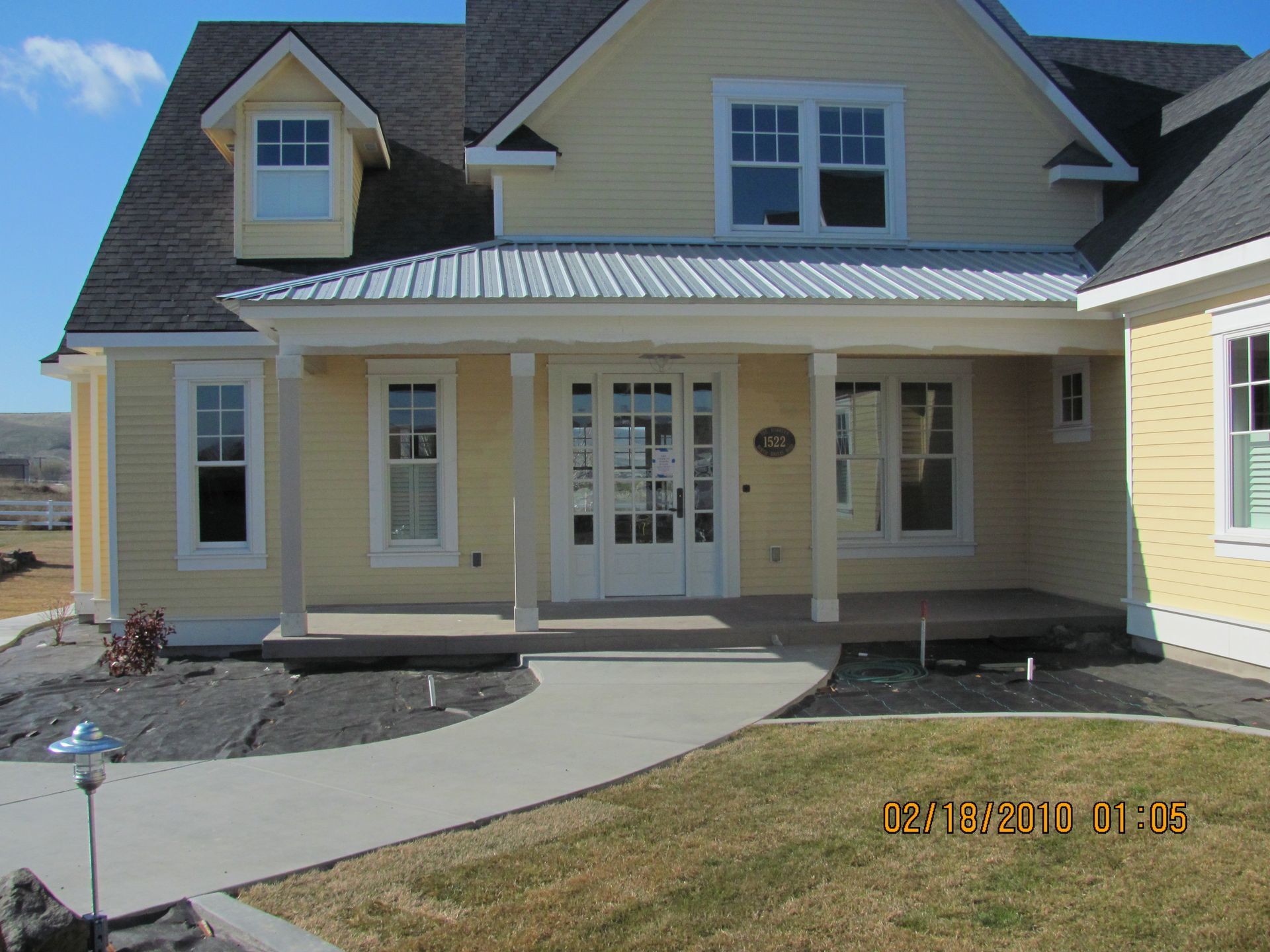 A yellow house with a porch and a gray roof