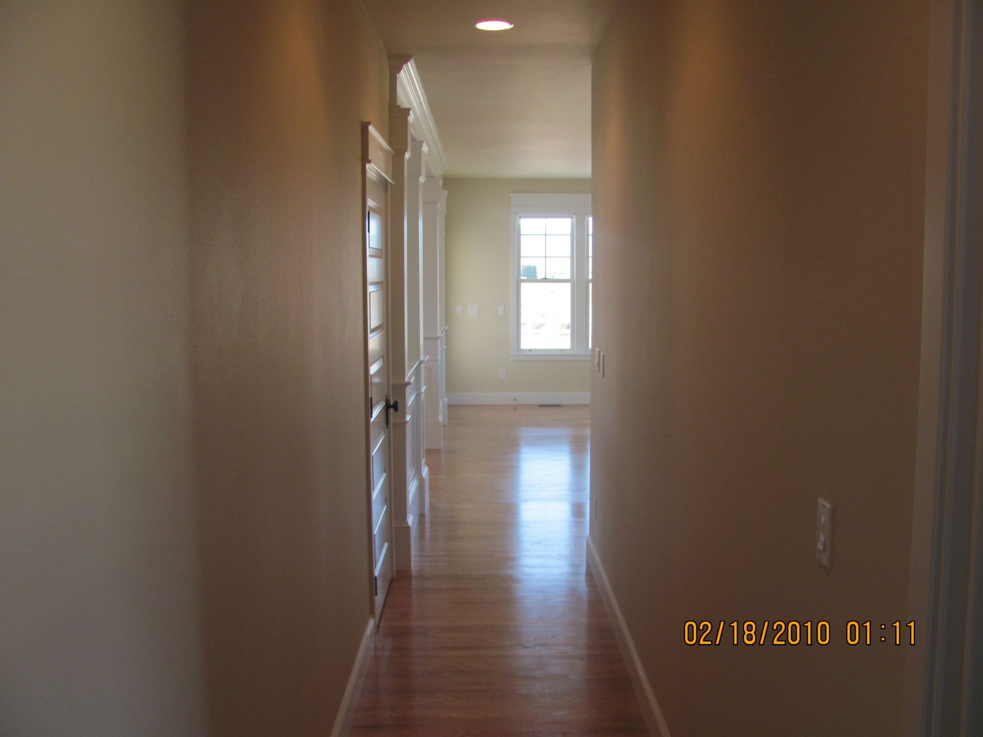 A long hallway with hardwood floors and a window