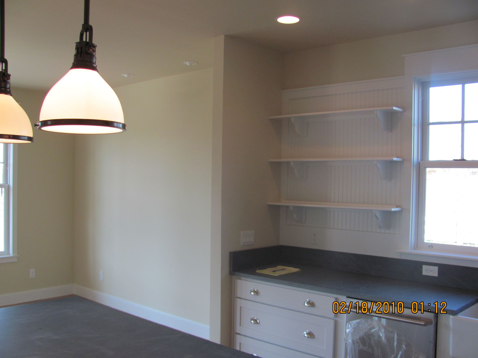 An empty kitchen with a window and shelves on the wall