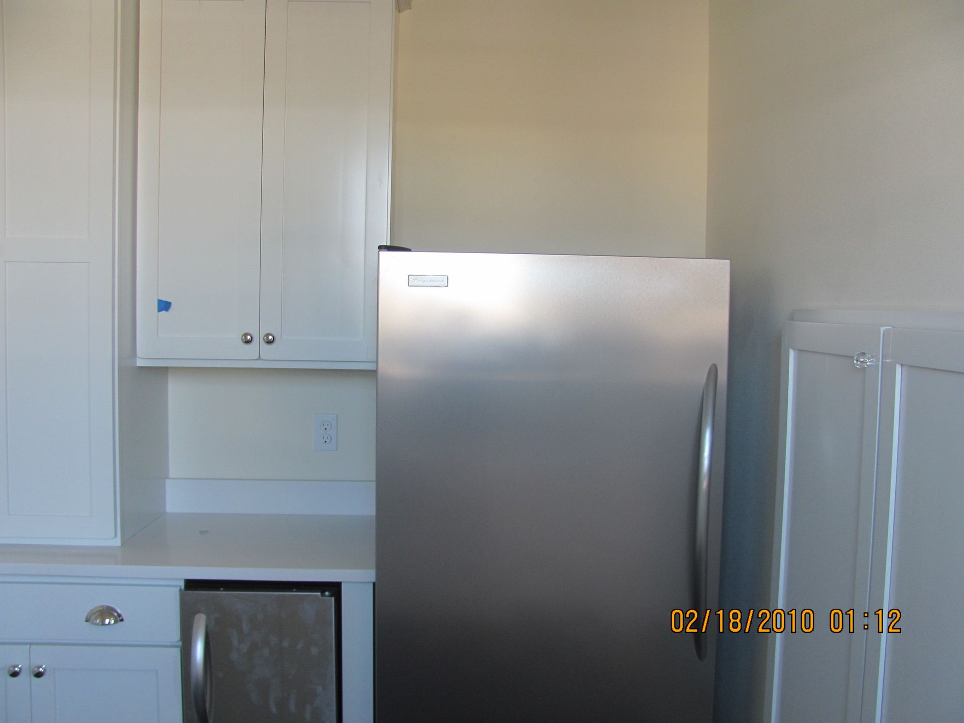 A stainless steel refrigerator is in a kitchen with white cabinets