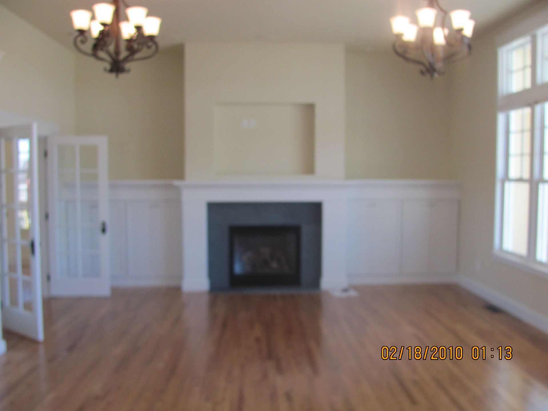 An empty living room with a fireplace and a chandelier