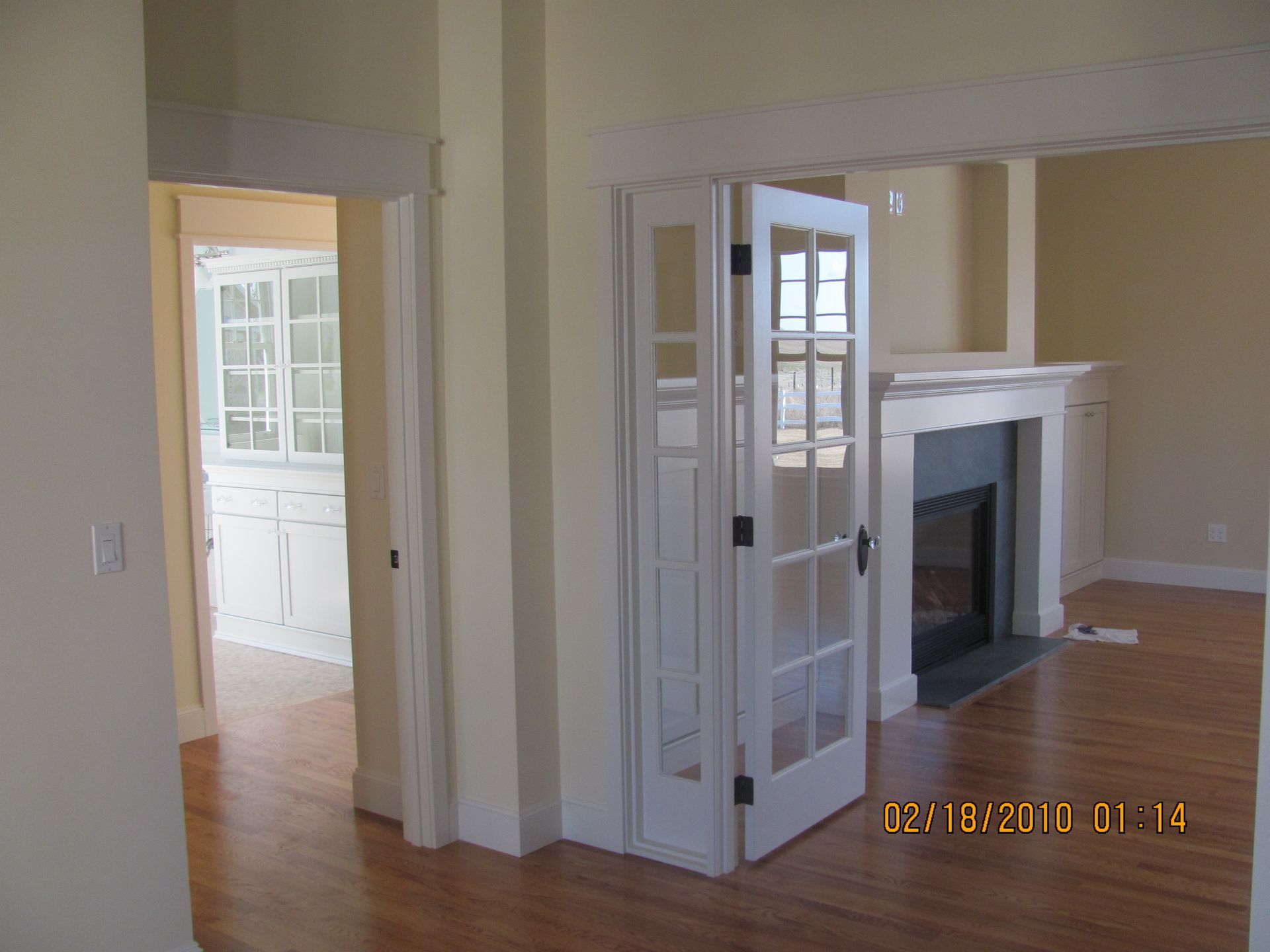 An empty living room with a fireplace and french doors
