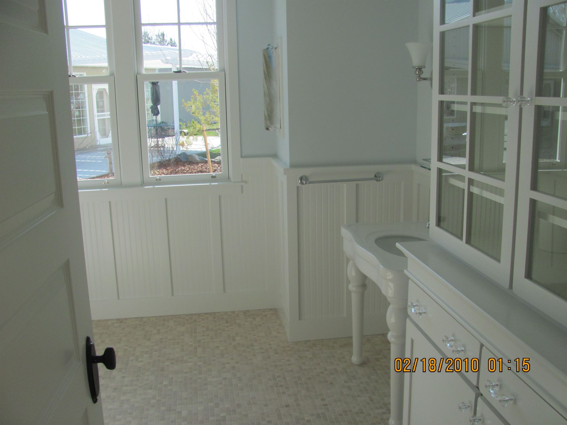 A bathroom with white cabinets and a sink and a window