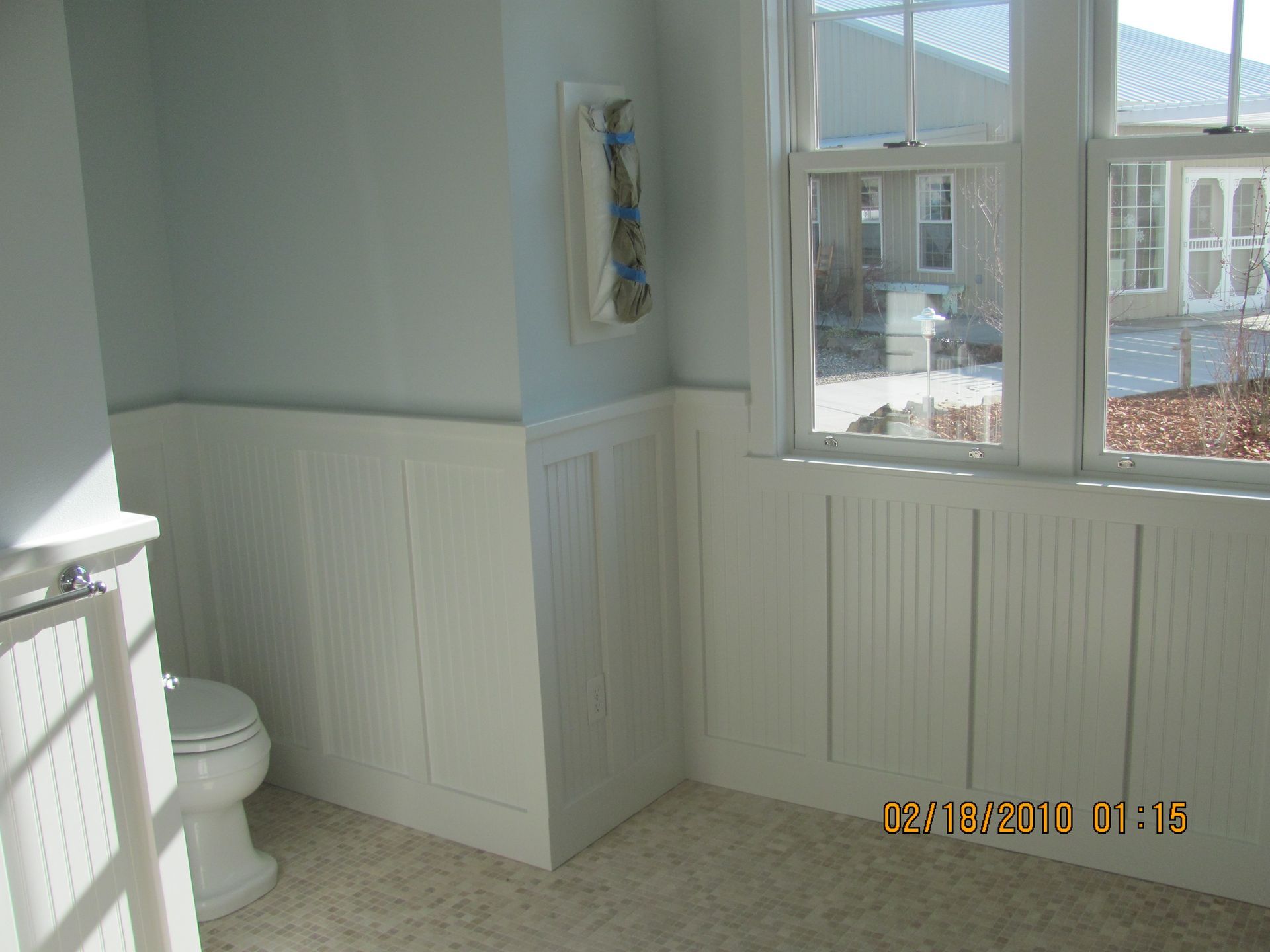 A bathroom with a toilet a window and a towel hanging on the wall