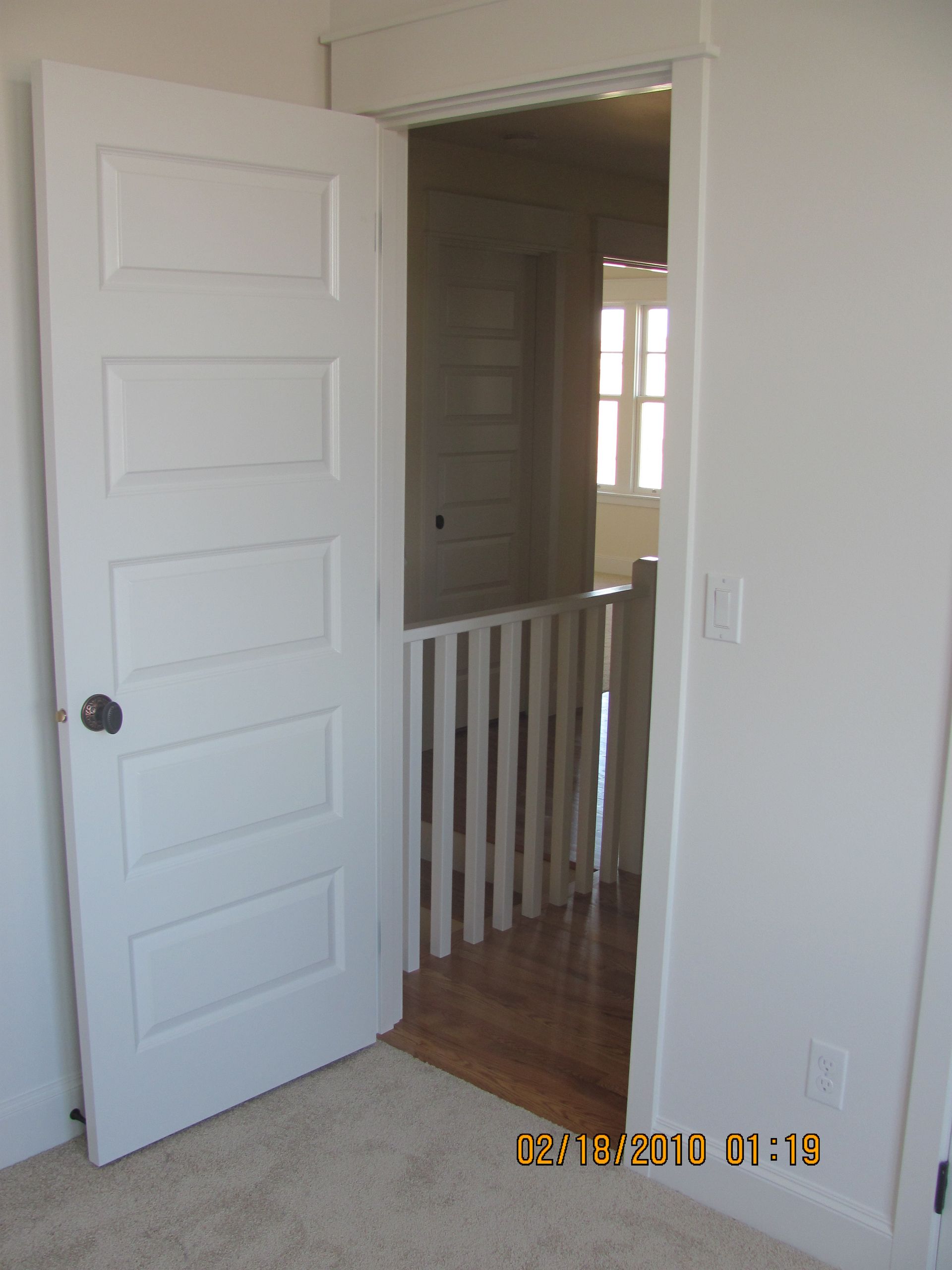 A white door is open to a room with a railing