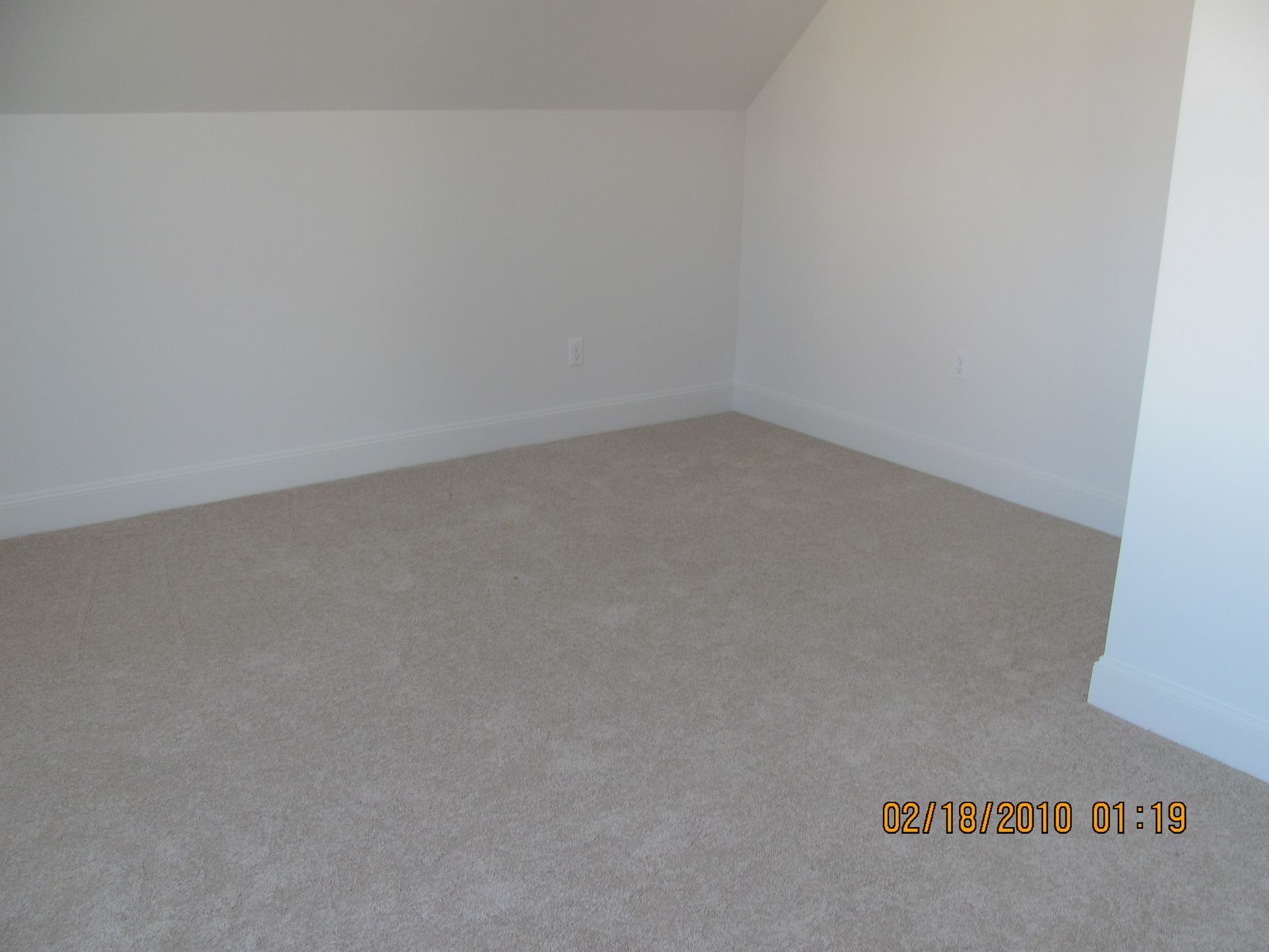 An empty room with a carpeted floor and white walls
