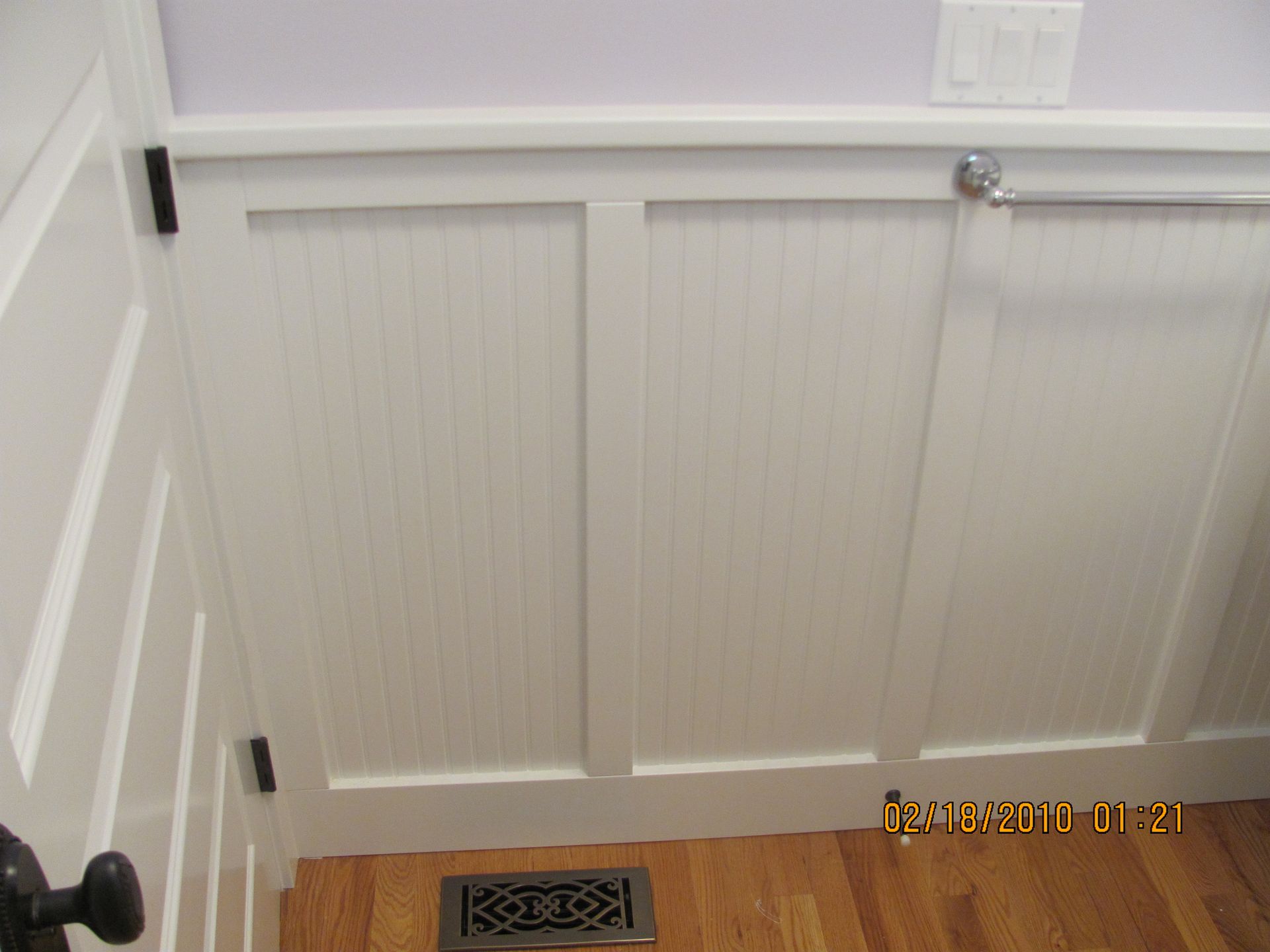 A white door with a black handle is sitting on a wooden floor.