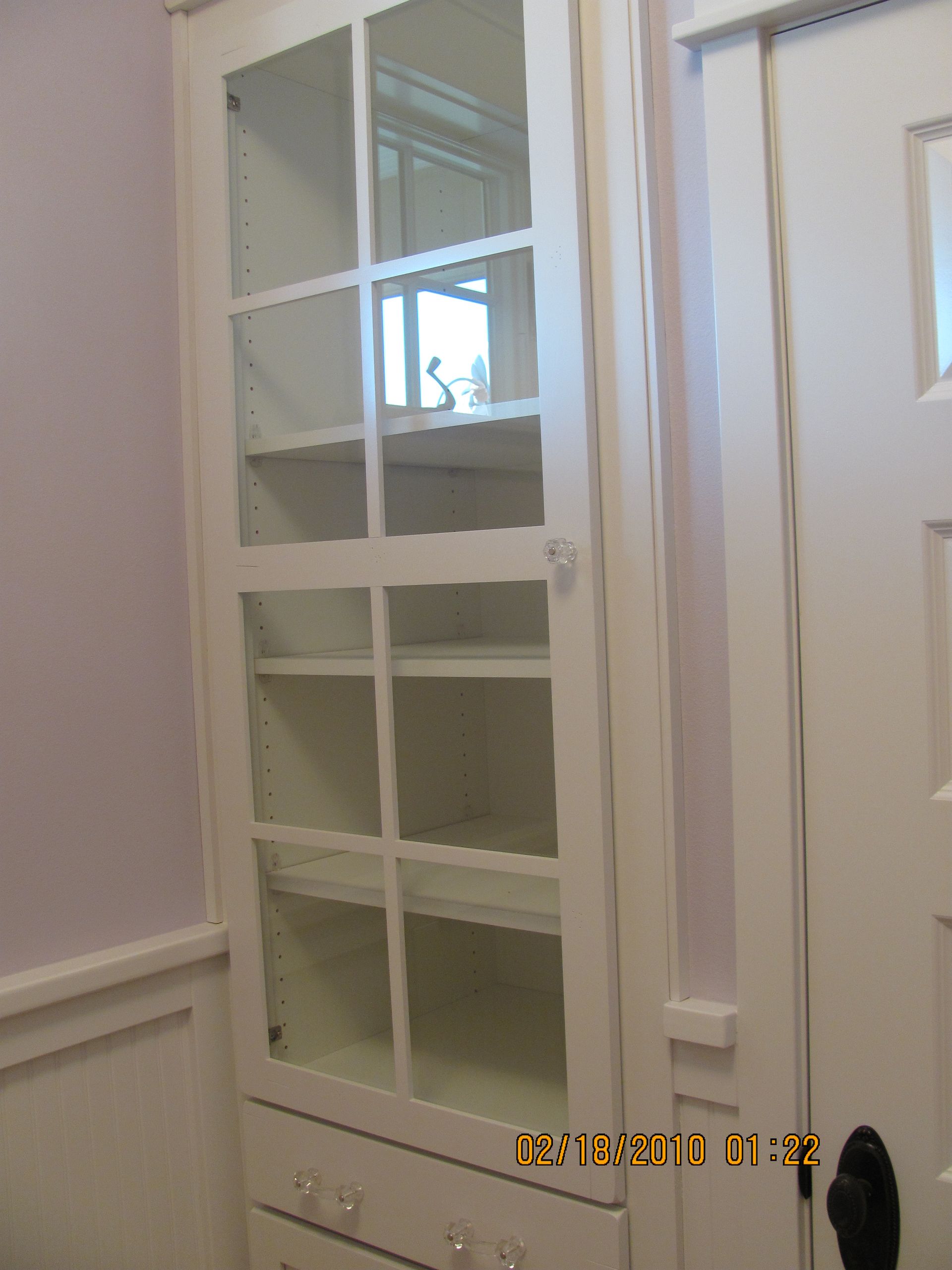 A picture of a white cabinet with glass doors was taken on october 15th 2013