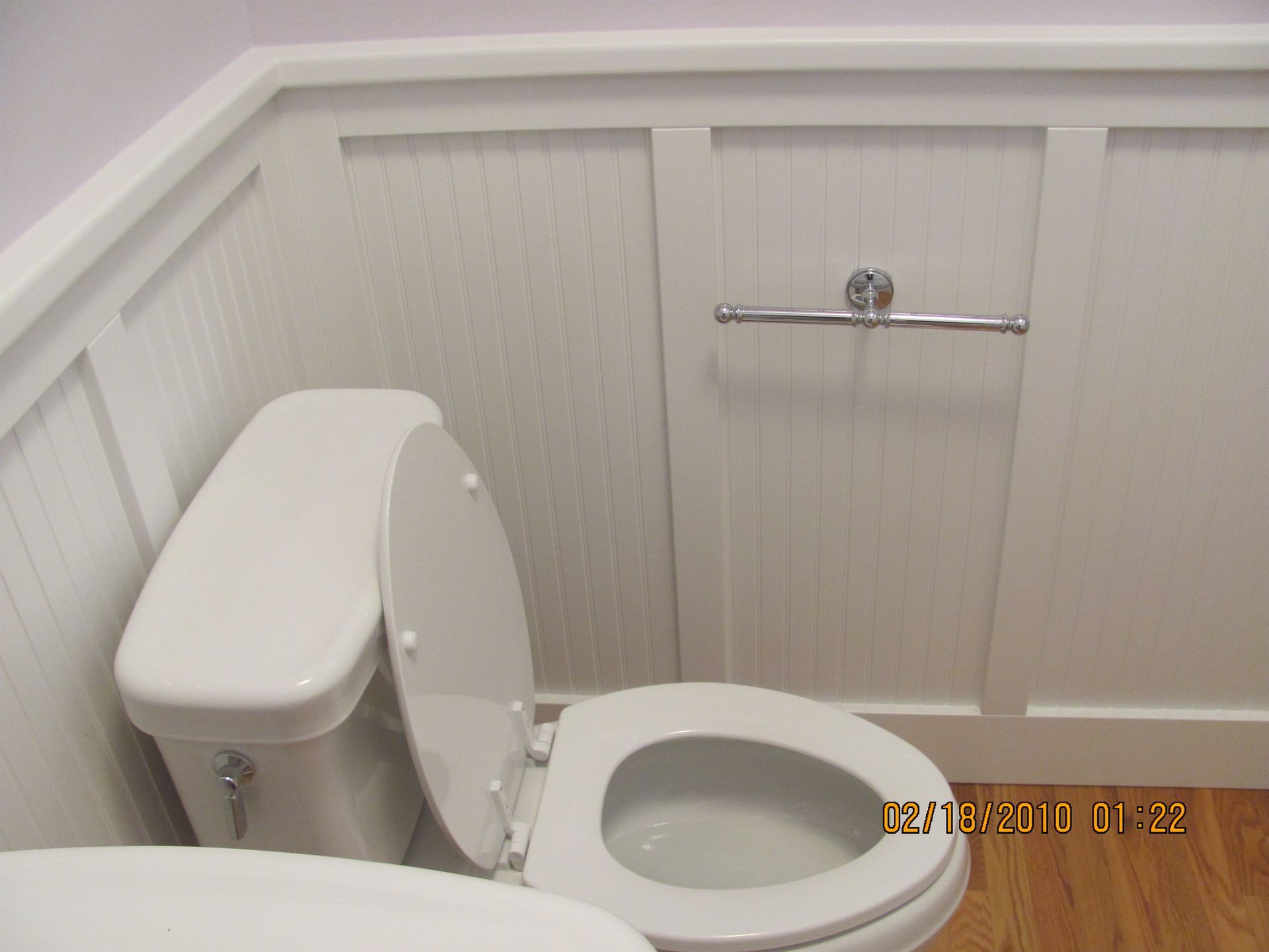 A bathroom with a toilet and a towel rack on the wall