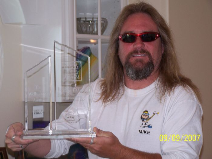 A man with long hair and a beard is holding a trophy