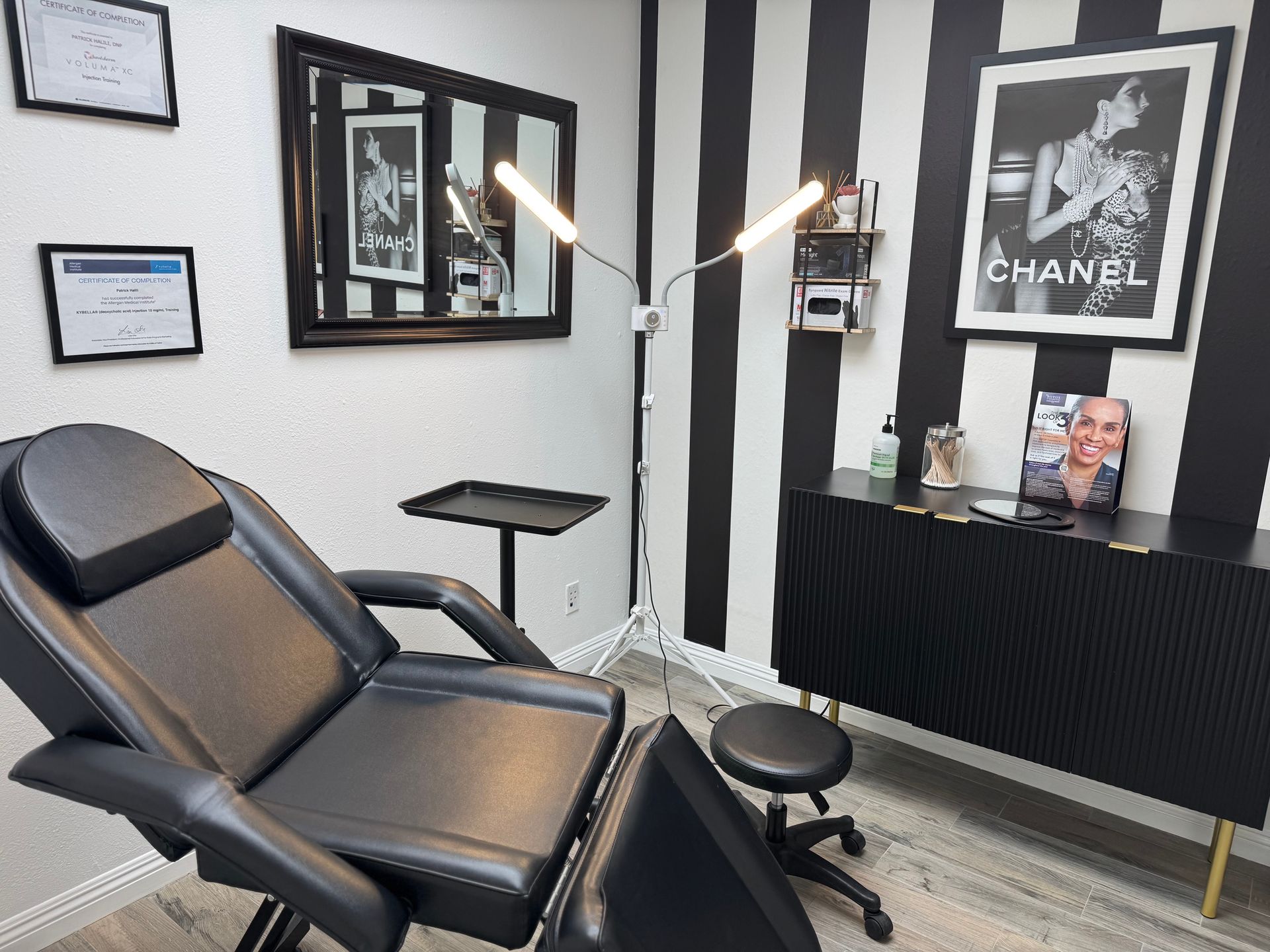 A black chair is in a room with a chanel poster on the wall.