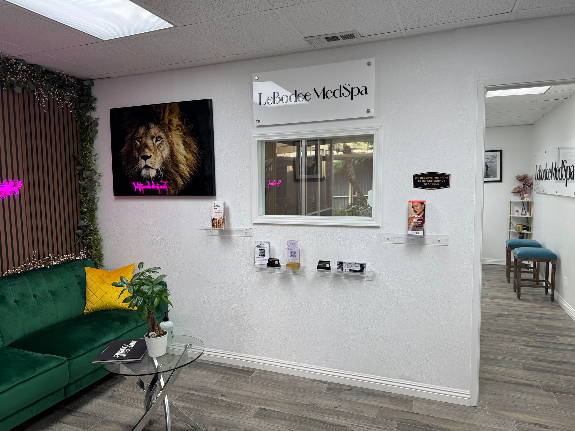 A waiting room with a green couch and a lion painting on the wall.