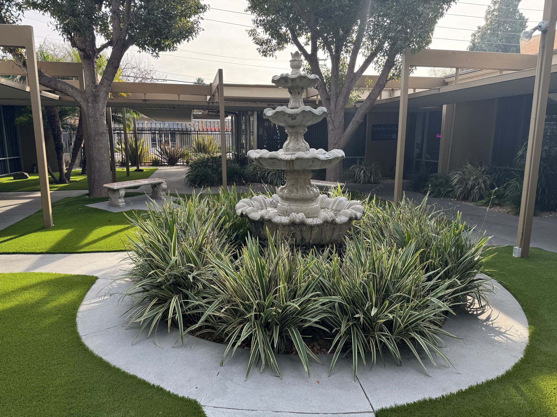 A fountain is in the middle of a lush green garden.